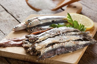 Marinated anchovies with salt and lemon on wooden table