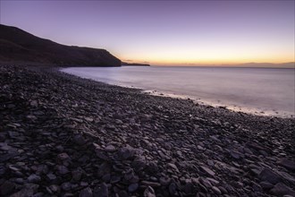 View of the sunrise over the Atlantic. View over a stone beach on a volcanic island. Cold lava