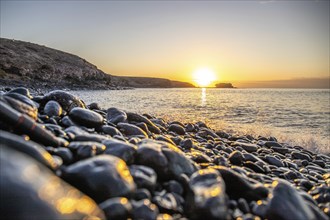 View of the sunrise over the Atlantic. View over a stone beach on a volcanic island. Cold lava