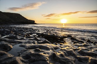 View of the sunrise over the Atlantic. View over a stone beach on a volcanic island. Cold lava