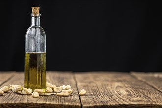 Fresh made Cashew Oil on an old wooden table (close-up shot, selective focus)