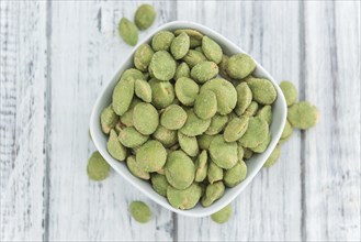 Peanuts (with Wasabi flavor) on an old wooden table as detailed close-up shot (selective focus)