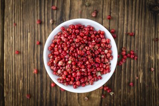 Pink Peppercorns as high detailed close-up shot on a vintage wooden table, selective focus