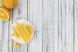 Some homemade orange popsicles (selective focus) on a vintage background