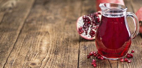 Homemade Pomegranate juice on an wooden table (selective focus) as detailed close-up shot