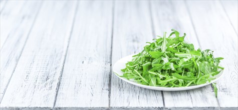 Wooden table with fresh Arugula as detailed close-up shot (selective focus)