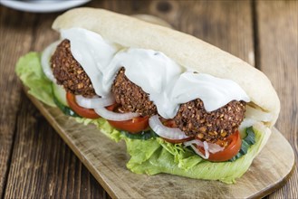 Wooden table with a fresh made Falafel Sandwich (selective focus, close-up shot)