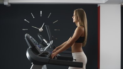 Sports concept. Pretty girl trains on background of clock