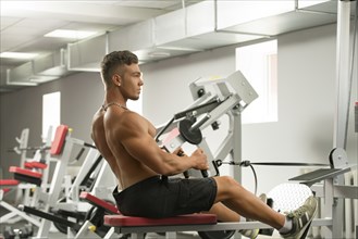 At gym. Photo of sexy young man trains on simulator