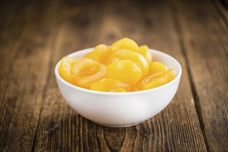 Canned Apricots on rustic wooden background (close-up shot)