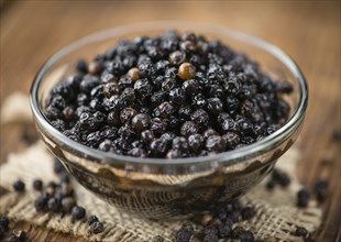 Preserved black Peppercorns on wooden background, selective focus, close-up shot