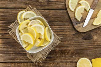 Fresh made Lemon (sliced) on an old and rustic wooden table (selective focus, close-up shot)