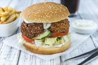 Homemade Falafel Burger (detailed close-up shot, selective focus) on a wooden table