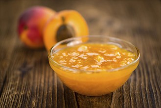 Apricot Jam as high detailed close-up shot on a vintage wooden table (selective focus)