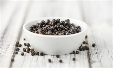 Preserved black Peppercorns on a wooden table as close-up shot