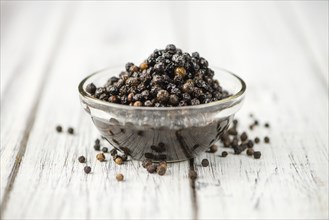 Wooden table with preserved black Peppercorns, selective focus, close-up shot