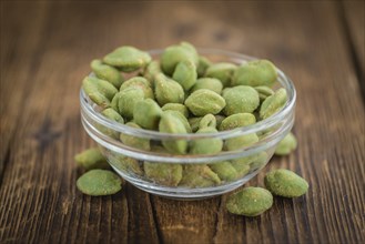 Peanuts (with Wasabi flavor) on an old wooden table as detailed close-up shot (selective focus)