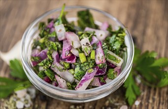 Healthy homemade Chimichurri on a wooden table as detailed close-up shot (selective focus)