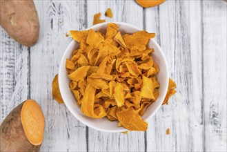 Sweet Potato Chips on an old wooden table as detailed close-up shot, selective focus