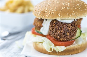 Homemade Falafel Burger (detailed close-up shot, selective focus) on a wooden table