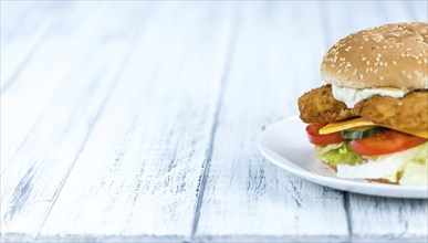 Wooden table with a fresh made Fish Burger (close-up shot, selective focus)