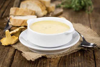 Chanterelle Soup as high detailed close-up shot on a vintage wooden table, selective focus