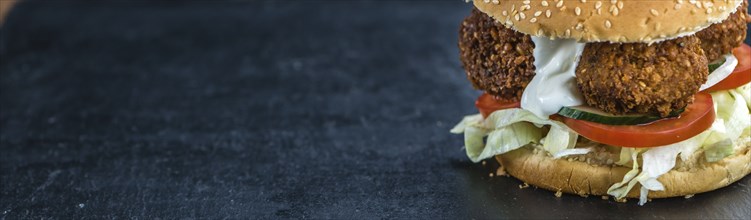 Homemade Falafel Burger on a dark slate slab (close-up shot, selective focus)