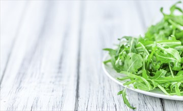 Wooden table with fresh Arugula as detailed close-up shot (selective focus)