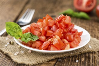 Tomatoes (diced) as high detailed close-up shot on a vintage wooden table (selective focus)