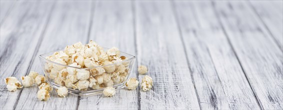 Popcorn as high detailed close-up shot on a vintage wooden table, selective focus