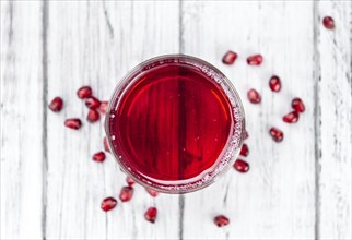 Homemade Pomegranate juice on an wooden table (selective focus) as detailed close-up shot