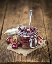 Cherry Jam as high detailed close-up shot on a vintage wooden table, selective focus