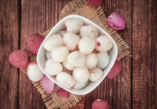 Litchis on rustic wooden background (close-up shot)