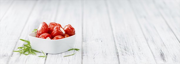 Filled Pimientos on an old wooden table as detailed close-up shot (selective focus)