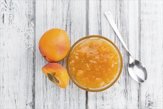 Apricot Jam as high detailed close-up shot on a vintage wooden table (selective focus)