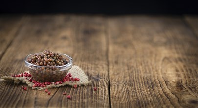 Fresh made Pink Peppercorns (preserved) on an old and rustic wooden table, selective focus,