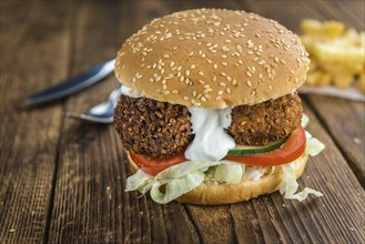 Vegetarian Falafel Burger on an old wooden table (close-up shot, selective focus)