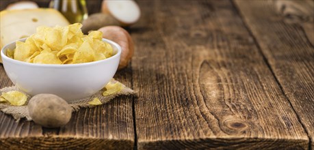 Cheese and Onion Potato Chips on an old wooden table as detailed close-up shot (selective focus)