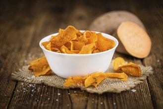 Sweet Potato Chips on an old wooden table as detailed close-up shot, selective focus