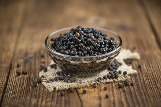 Preserved black Peppercorns on a wooden table as close-up shot