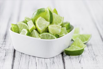 Sliced Limes on rustic wooden background (close-up shot)