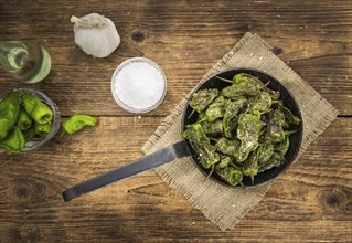 Pimientos de Padron on rustic wooden background as close-up shot