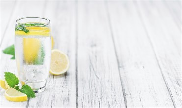 Lemonade (with Balm) as high detailed close-up shot on a vintage wooden table (selective focus)