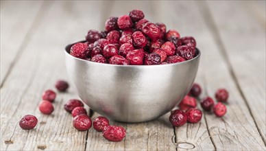 Healthy Cranberries (dried) on a wooden table as detailed close-up shot (selective focus)