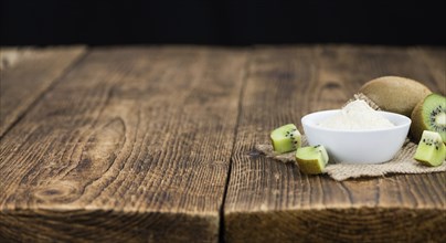 Bowl with fresh made Kiwi powder (close-up shot, selective focus) on an old wooden table