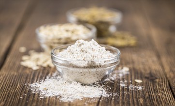 Some Oat Flour on a vintage wooden table (selective focus, close-up shot)