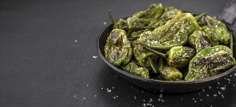 Some Pimientos de Padron on a slate slab as detailed close-up shot, selective focus