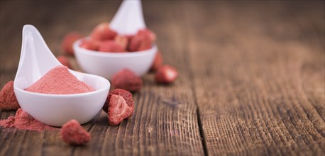 Strawberry powder as high detailed close-up shot on a vintage wooden table, selective focus