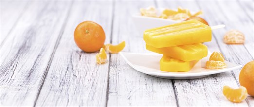 Homemade Tangerine Popsicles with some fresh fruits (close-up shot) on a vintage background