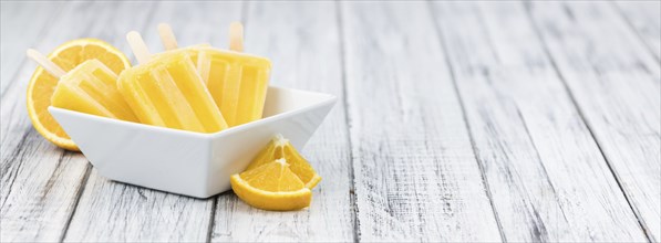 Some homemade orange popsicles (selective focus) on a vintage background